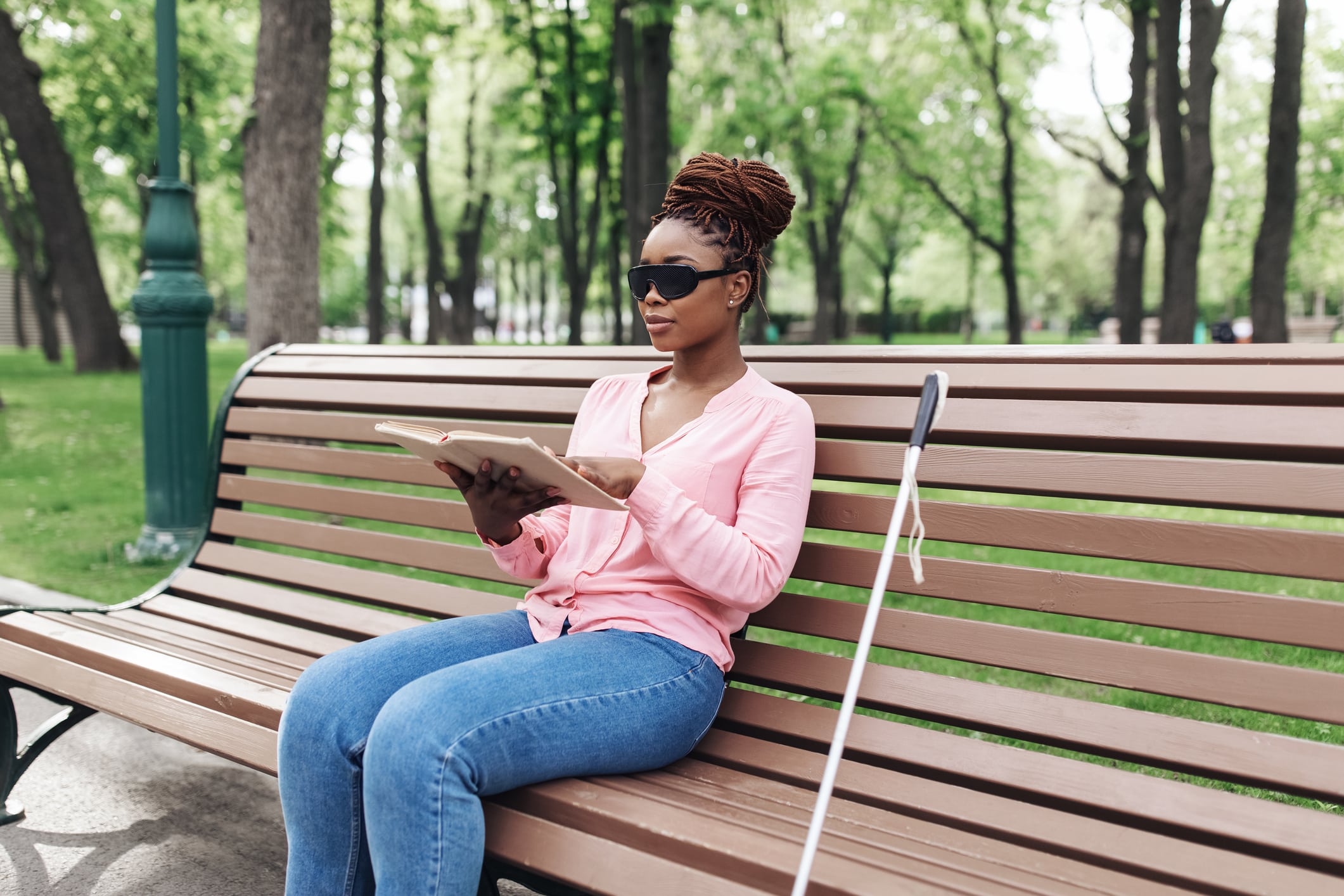 Lady on park bench reading braille